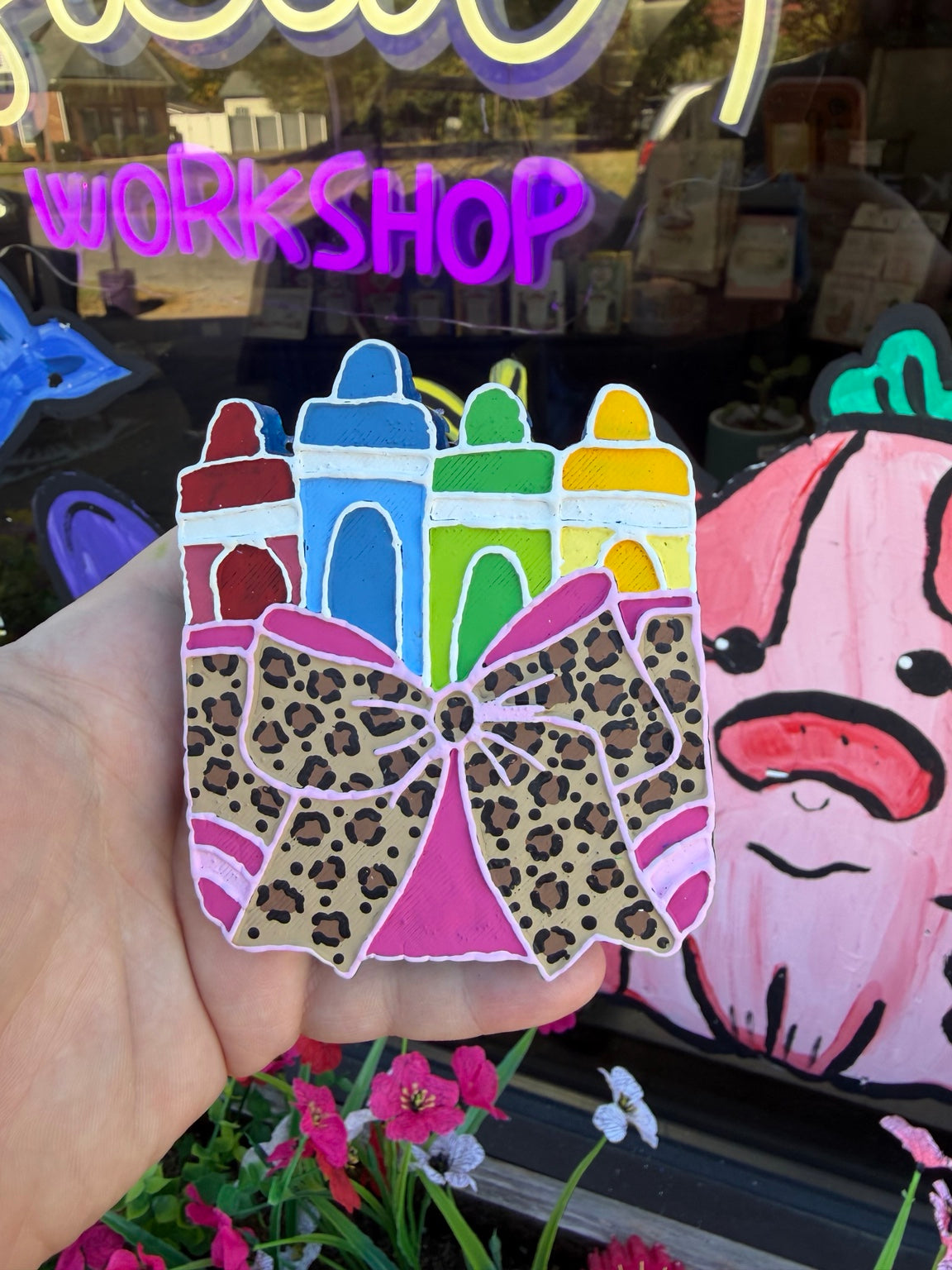 Handmade crayon bow freshie with four crayons and a large leopard print bow, displayed outside Whimsical Workshop